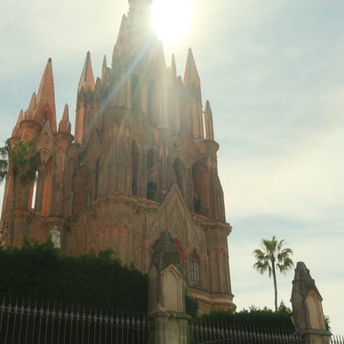 Kirche in San Miguel de Allende, Mexiko, mit hohen gotischen Türmen unter hellerer Sonne und teilweise bewölktem Himmel.