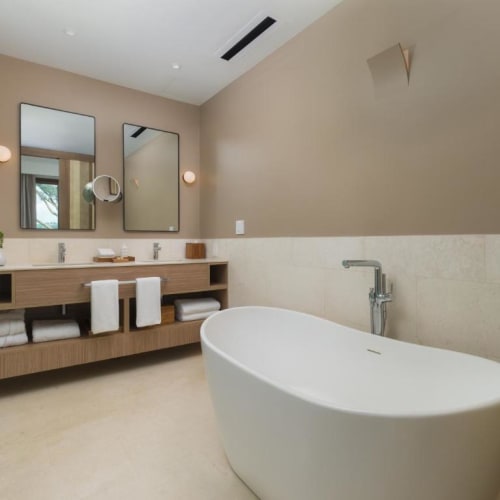 Modernes Badezimmer mit freistehender Badewanne, Doppelwaschbecken und minimalistischer Dekoration in neutralen Tönen.