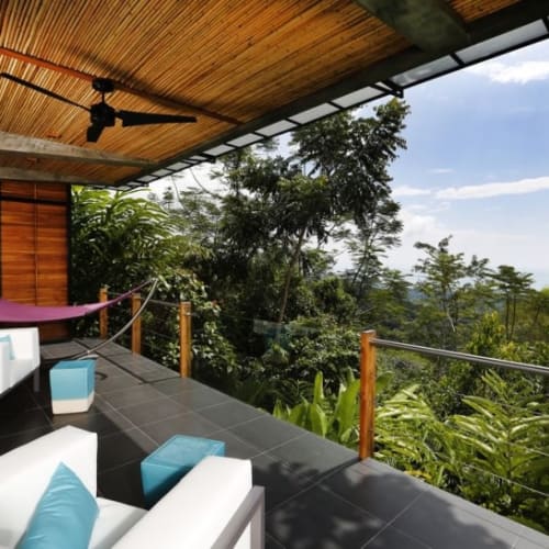 A spacious outdoor terrace at a boutique hotel with white sofas, a hammock, and lush green forest views in Uvita, Costa Rica.