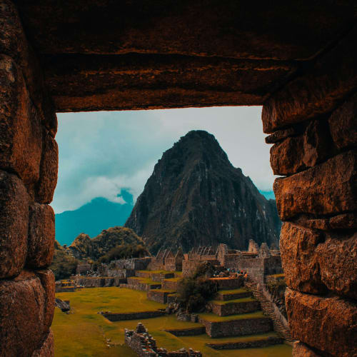 Aussicht auf Machu Picchu, eingerahmt von alten Steinmauern mit Huayna Picchu im Hintergrund.