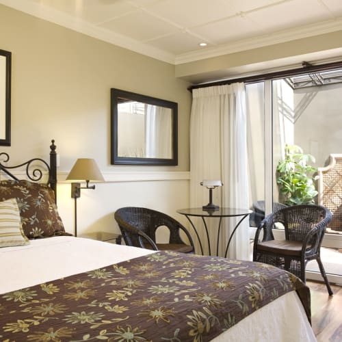 Cozy bedroom with a large bed, decorative pillows, and a small balcony door with outdoor seating area.