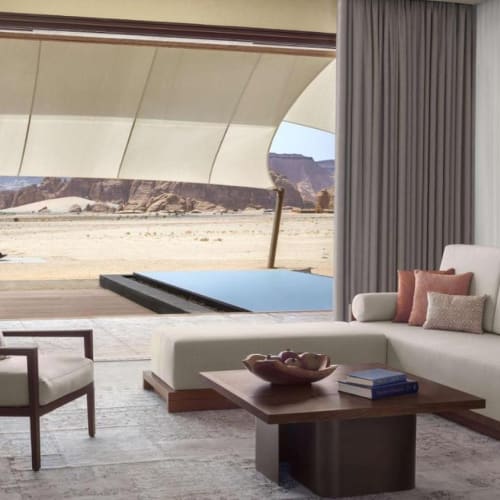 Luxurious living room with large windows overlooking a desert landscape and modern furniture.