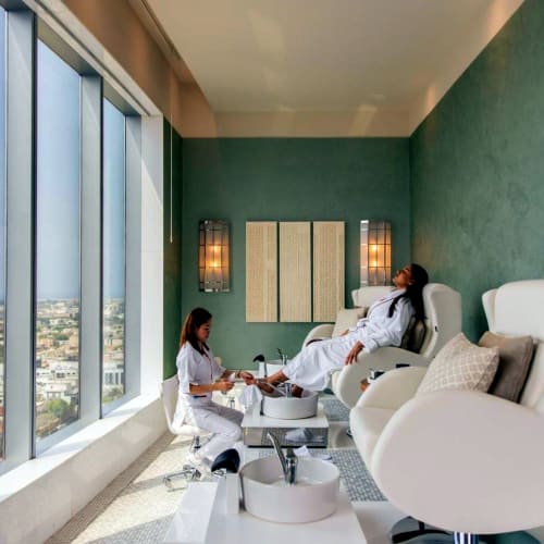 A woman receiving a pedicure treatment at a luxurious spa with large windows overlooking the city.