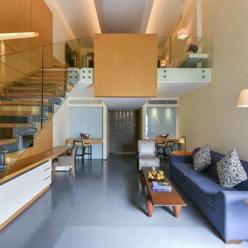 Modernes Hotellobby mit einer Treppe, Sitzecke mit blauer Couch und Glasterrassen auf der oberen Ebene.