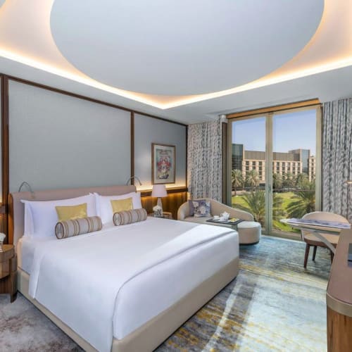 Luxuriöses Deluxe-Kingsize-Zimmer mit modernischer Einrichtung, großem Fenster mit Stadtblick und eleganten Möbeln.