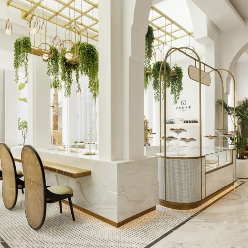 Elegantes Interieur eines Cafés mit weißen Wänden, hängenden Pflanzen und moderner Einrichtung.