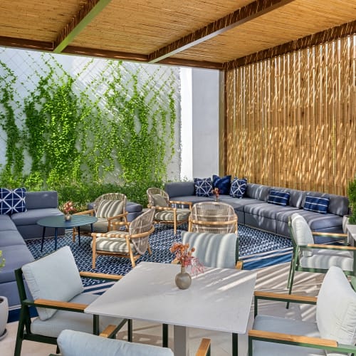 Außenbereich eines Strandresort-Restaurants mit modernen Möbeln, Topfpflanzen und Grünpflanzen an der Wand.