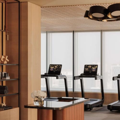 Drei Laufbänder vor großen Fenstern in einem modernen Fitnessstudio mit minimalistischen Design.