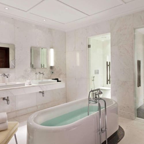 Luxuriöses modernes Badezimmer mit freistehender Badewanne, Doppelsinkbecken und begehbarer Dusche in einem Hotellayout.