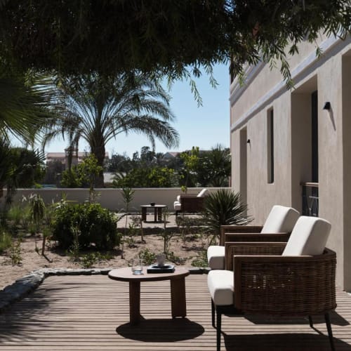 Entspannter Außenbereich mit gepolsterten Stühlen, einem Holztisch und üppigem Grün, Teil einer Suite im The Chedi El Gouna.