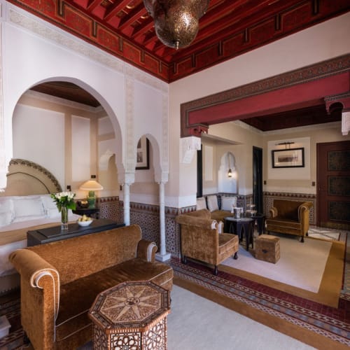 Luxuriöse Hotellounge mit marokkanischer Dekoration, mit bequemen Sofas, kunstvollem Holzwerk und traditionellen marokkanischen Bögen.