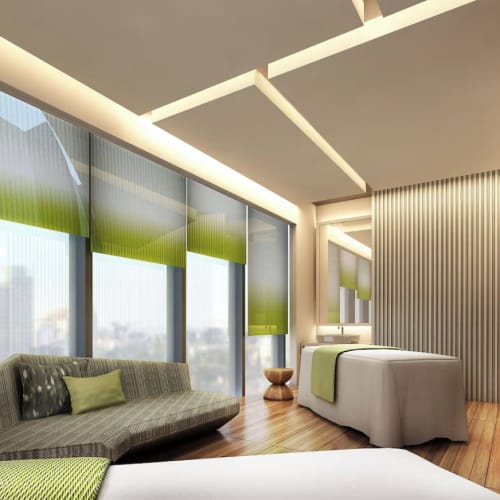 Ein modernes Hotelzimmer mit großen Fenstern, einem Sofa mit Kissen und einem Bett in der Ecke, mit zeitgemäßer Dekoration und grünen Akzenten.