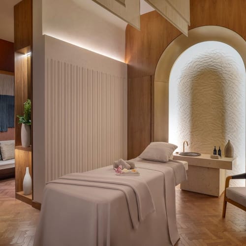 Ein luxuriöser Massagebereich im St. Regis Riyadh mit Massagebett, weichem Licht und eleganter Dekoration.