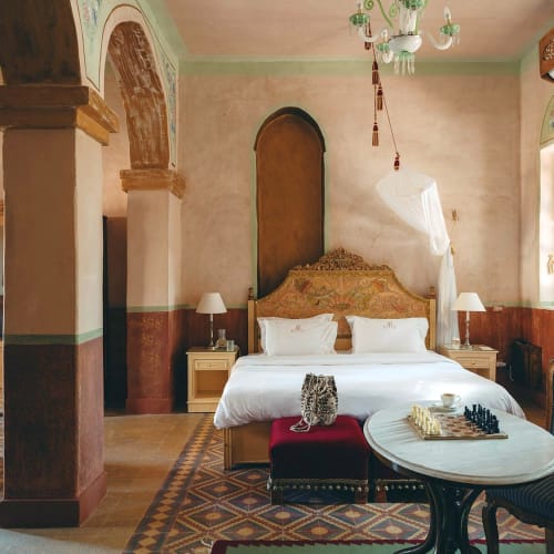 Luxuriöse Junior-Suite mit dekoriertem Kopfteil, weißer Bettwäsche und antiken Möbeln in einem stilvollen Hotel.
