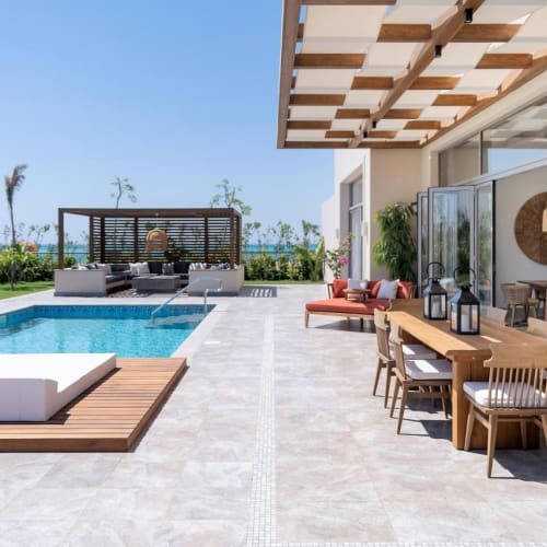 Luxury outdoor area with a swimming pool, lounge chairs, and a patio dining setup at a resort.