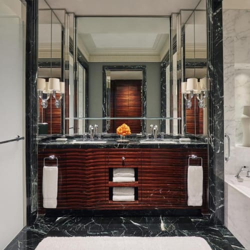 Luxurious bathroom with a double sink vanity, a marble bathtub, and elegant decor, reflecting a high-end hotel environment.