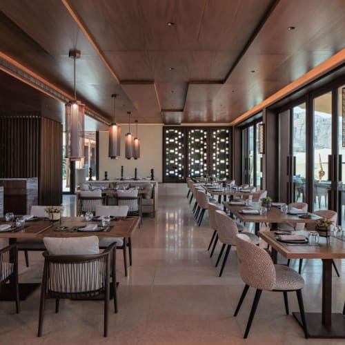 Elegantes Restaurant mit Holzakzenten, moderner Beleuchtung und großen Fenstern, die einen Blick nach draußen bieten.