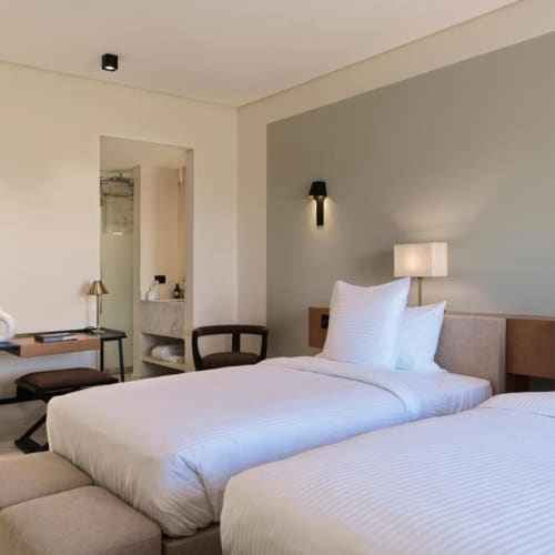 Twin beds in a modern hotel room with minimalist decor and soft lighting.