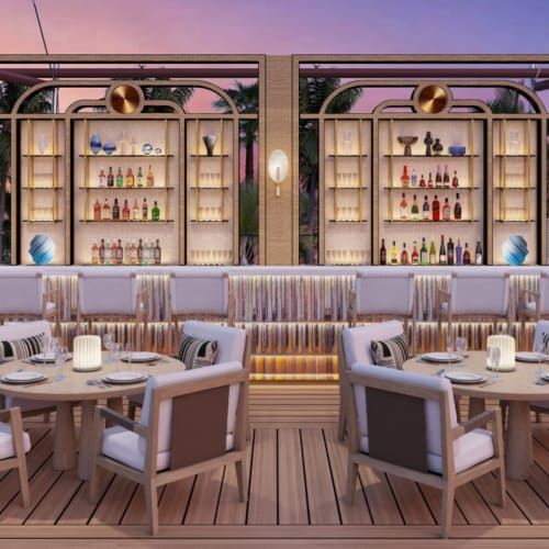 Elegant outdoor bar area with a fully stocked shelf and seating at sunset.