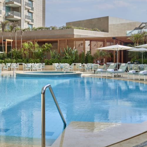 Villaer Poolbereich mit Sonnenliegen, Sonnenschirmen und üppigem Grün im Four Seasons Hotel Kairo am Nile Plaza.