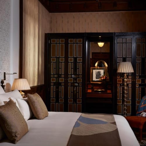 Luxuriöses Schlafzimmer mit großem Bett, mehreren Kissen und elegantem Beleuchtungssystem in einem reich verzierten Hotelzimmer.