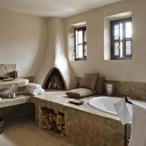 Luxurious bathroom in Dar Ahlam Garden Suite with a corner bathtub, fireplace, and towels.