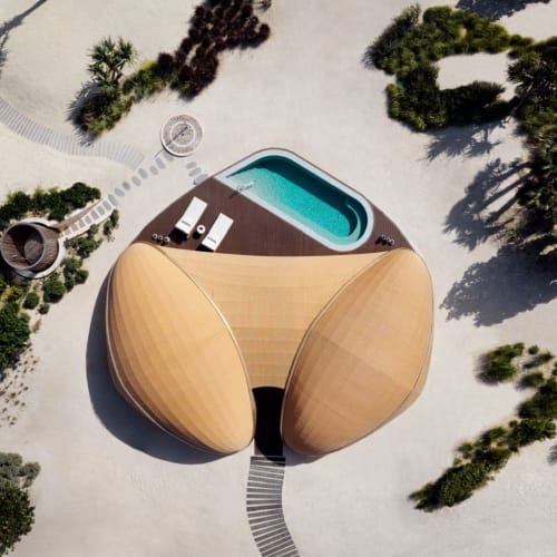 Luftaufnahme eines modernen Gebäudes mit Holzauskleidung, einem kleinen Pool und umgebenden Bäumen in einem Resort.