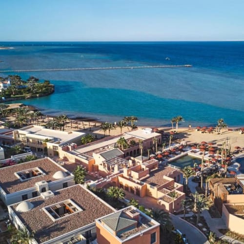 Luftaufnahme von The Chedi El Gouna mit Blick auf das Meer im Hintergrund, zeigt Resort-Gebäude und einen Sandstrand.