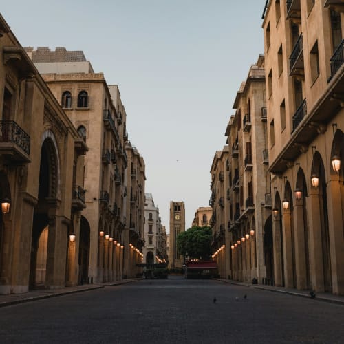 Empty street lined with historic buildings and streetlights in Beirut's old town, early in the morning.