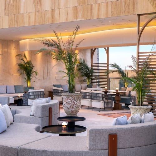 Eleganter Lounge-Bereich mit modernen Möbeln und zahlreichen Topfpflanzen in der St. Regis Riyadh Stella Sky Lounge.