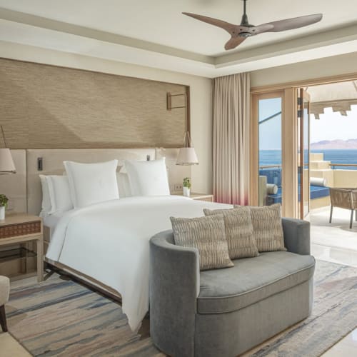 Luxus-Suite mit großem Bett, Sitzecke und Balkon mit Blick auf das Meer in einem Four Seasons Resort.
