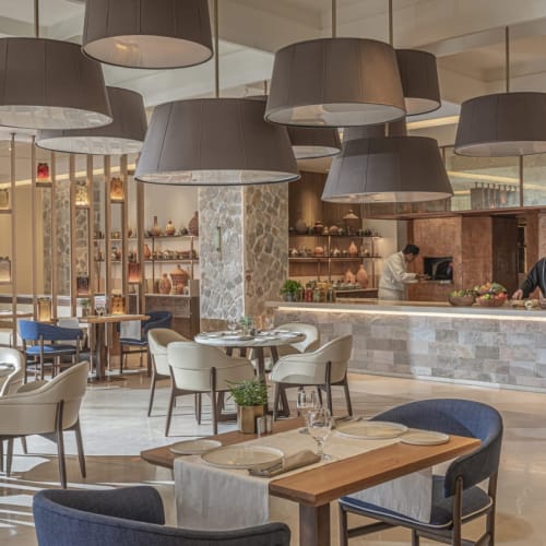 Elegantes Restaurant mit modernen Hängeleuchten, runden Tischen und schicken Stühlen in einer luxuriösen Umgebung.