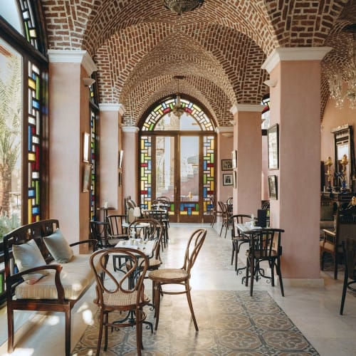 Elegantes Innendrestaurant mit gewölbter BacksteinDecke, großen bunten Glasfenstern und antikem Mobiliar.
