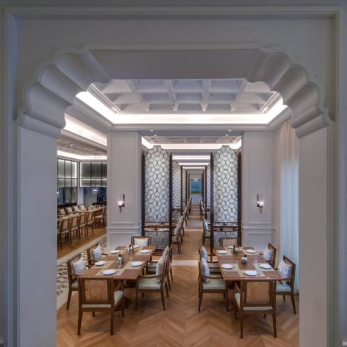 Eleganter Speisesaal mit Holztischen und Stühlen, getrennt durch dekorative Faltwände, in einem luxuriösen Hotelrestaurant.