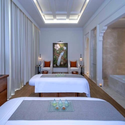 Luxus Spa-Zimmer mit Massageliegen, eleganter Einrichtung und einem kleinen Whirlpool-Bereich.