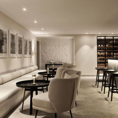 Ein modernes, gemütliches Bar mit weißen Sitzgelegenheiten und schwarzen Tischen in einer sanft beleuchteten Lounge.