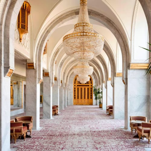 Elegant corridor inside a luxurious hotel with marble columns, ornate chandeliers, and comfortable seating areas.