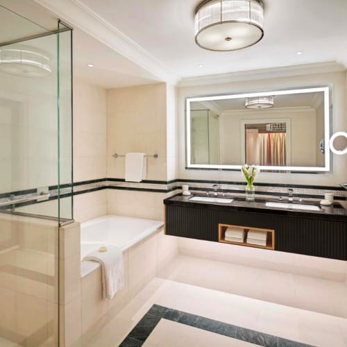 Luxuriöses Hotel Badezimmer mit Badewanne, großem beleuchteten Spiegel und modernem Design.