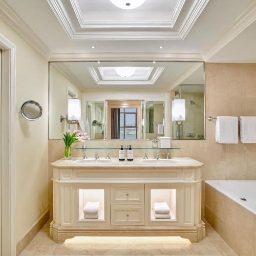 Luxuriöses Badezimmer mit großem Spiegel, Doppelwaschbecken, Badewanne und eleganter Dekoration.