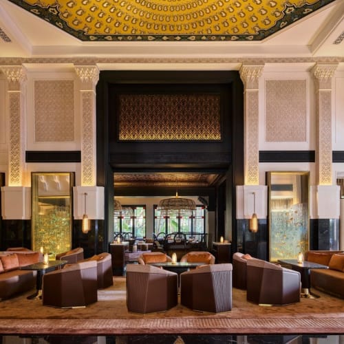 Luxuriöse Hotellobby mit eleganten Sitzgelegenheiten, kunstvollem Deckenboden und dekorativen Lichtinstallationen.
