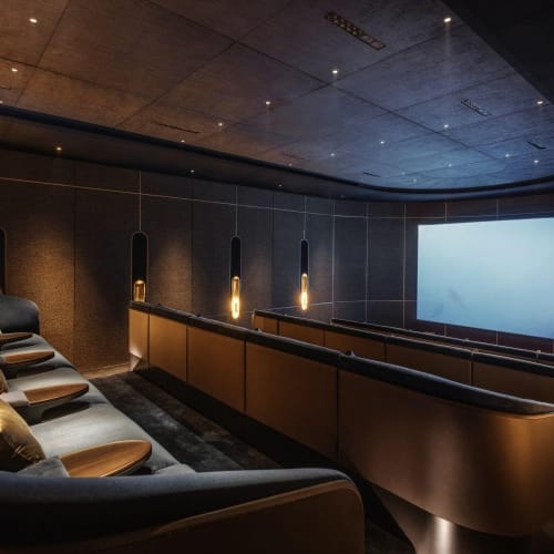 Luxuskino mit gebogener Sitzanordnung, dunklen Wänden und großem Bildschirm in einem privaten Vorführraum.