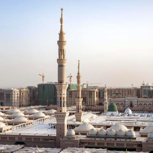 Blick auf die Moschee mit mehreren Minaretten und Kuppeln in einer städtischen Umgebung bei Tageslicht.
