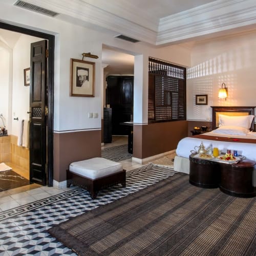 Luxurious deluxe suite in a hotel room with a large bed, bedside lamps, and elegant decor.