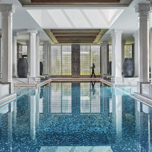 Luxuriöses Hallenbad im Spa des Four Seasons Hotels Bahrain Bay, mit dekorativen Säulen und großen Vasen.