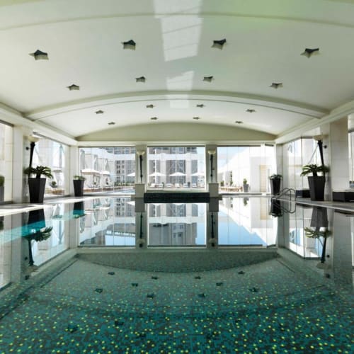 Innenpool in einem luxuriösen Hotel mit großen Fenstern und Topfpflanzen.