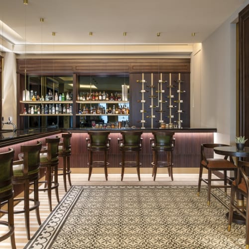 Elegante Bar mit einem geschwungenen Tresen, Hockern und einem gemusterten Boden in einem luxuriösen Hotelaus setz.