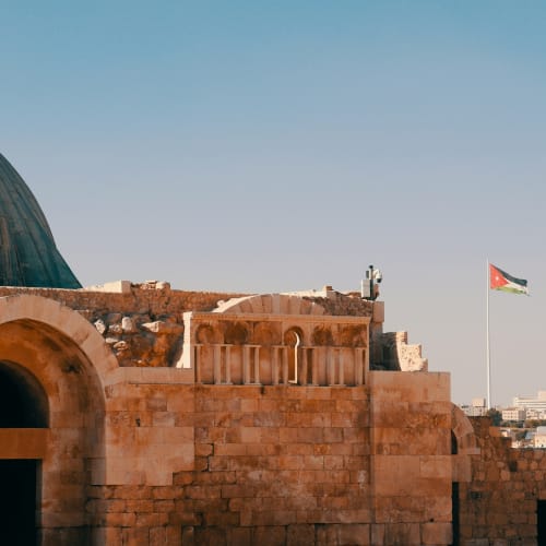 Alte Steinruinen mit einer schwarzen und roten Flagge, die im klaren Himmel von Amman, Jordanien, weht.