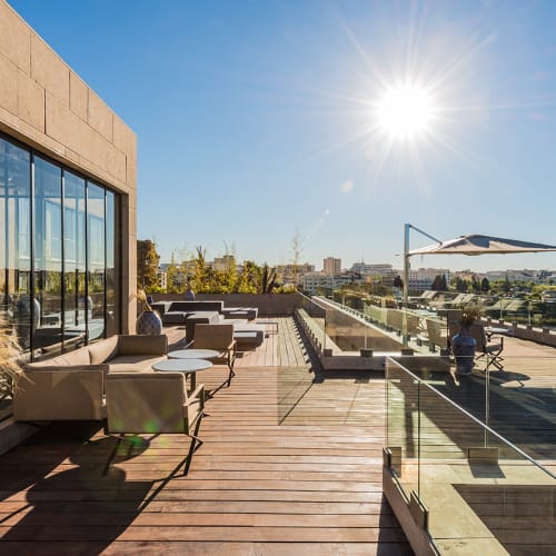 Sonnendurchflutete Dachterrasse des Hotel Sahrai mit moderner Außensitzgruppe, Glasgeländern und Blick auf eine Stadtkulisse unter klarem blauem Himmel.