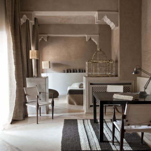 Eine luxuriöse Suite mit einem Sitzbereich und einem Bett im Hintergrund, dekoriert mit eleganten Möbeln und Wandkunst.