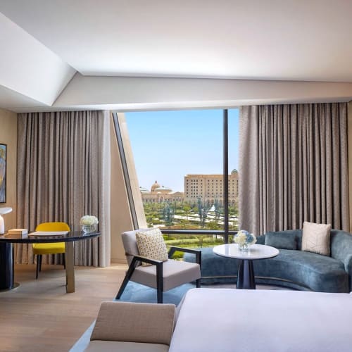 Ein luxuriöses Hotelzimmer mit Sitzbereich und großem Fenster mit Blick auf die Stadt.